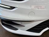the front end of a white car with a sticker on it ' s bumper