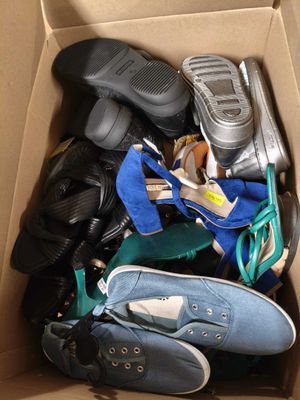plusieurs paires de chaussures dans une boîte en carton posée sur le sol