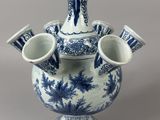a blue and white vase with three cups in it
