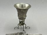 une petite coupe en argent et un couteau posés sur un socle