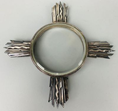 un objet en forme de croix argentée sur une surface blanche