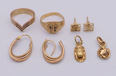 plusieurs bagues et boucles d'oreilles en or posées sur une surface blanche