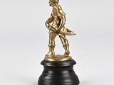 figurine en laiton représentant un garçon tenant un poisson, posée sur un socle noir