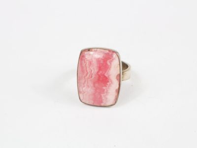gros plan d'une bague en pierre rose sur une surface blanche