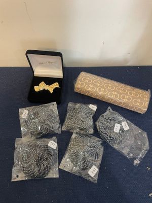 several pieces of jewelry are sitting on a table next to a roll of fabric