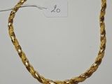 a close up of a gold necklace on a white surface