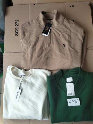 three men ' s sweaters are sitting on a cardboard box