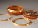 three gold rings and a ring box with a picture of a woman