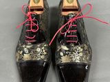 pair of black and gold shoes with red laces on them