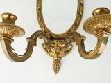 a gold wall sconce with two candles on it