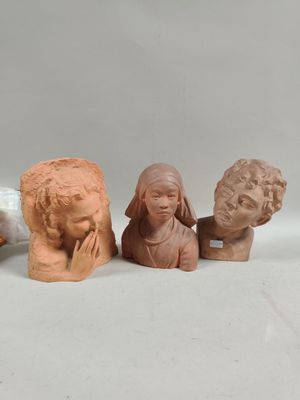 three clay heads of people sitting next to each other on a white surface