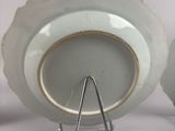 two white plates with gold rims sitting on a stand