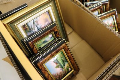 beaucoup de photos encadrées dans une boîte posée par terre