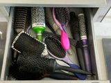 a drawer full of hair brushes and combs in a bathroom