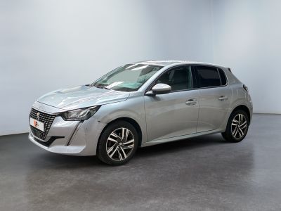Une voiture argentée est garée dans une pièce aux murs blancs.