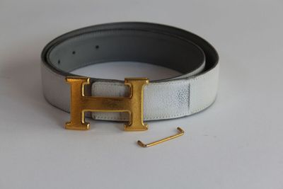 boucle en forme de « H » en argent et or sur une ceinture en cuir blanc