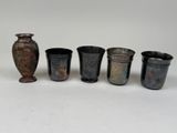 Plusieurs vases sont alignés les uns à côté des autres sur une surface blanche