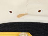 a close up of a hat with a gold pin on it