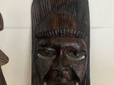 two wooden masks that are on a shelf next to each other
