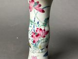 a white vase with pink flowers on it sitting on a table