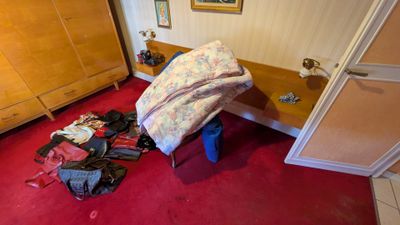 un tapis rouge dans une chambre où se trouvent un lit et une commode