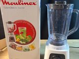un mixeur posé sur une table à côté d'une boîte de nourriture