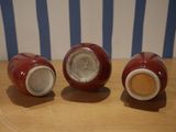 three red vases sitting on a table next to each other