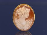 Une broche plaquée or représente le profil d'une femme.