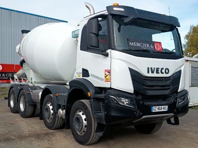 un camion de ciment blanc garé devant un immeuble