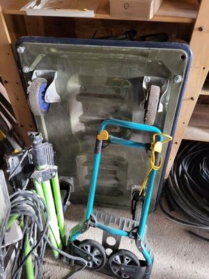 a small blue cart with a green handle next to a pile of tools