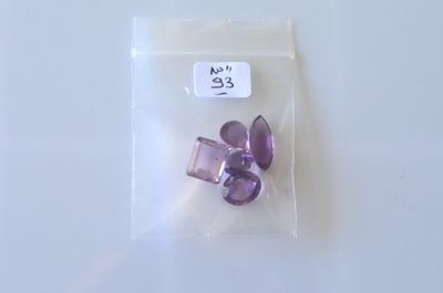 un petit sachet de perles violettes posé sur une table blanche