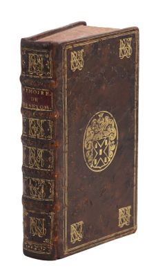 un vieux livre avec une couverture plaquée or sur fond blanc