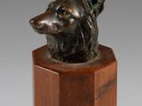 une image représentant une tête de chien en bronze posée sur un socle en bois