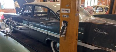 une voiture noire et blanche et une voiture verte dans un garage