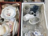 two baskets with dishes and cups in them on the floor