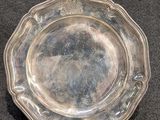 un plat en argent ancien posé sur une table, sur fond noir