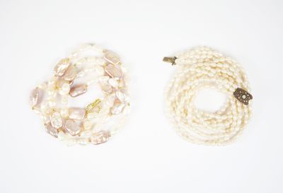 deux rangs de perles blanches et un fermoir en or sur fond blanc