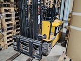 un chariot élévateur dans un entrepôt, avec des palettes de bois en arrière-plan