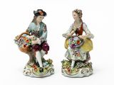 two figurines of a man and a woman with baskets of flowers