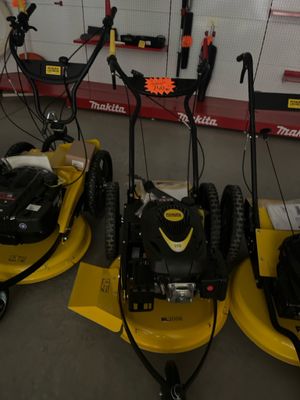 Trois tondeuses à gazon sont alignées les unes à côté des autres dans un garage