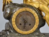 a gold statue of a woman sitting on a rock with a clock