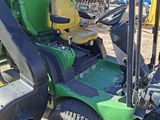 a green and black tractor parked in the dirt
