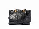 a black quilted handbag with gold hardware on the handles