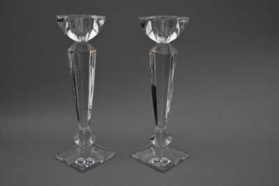 paire de bougeoirs en cristal sur un socle, sur fond gris