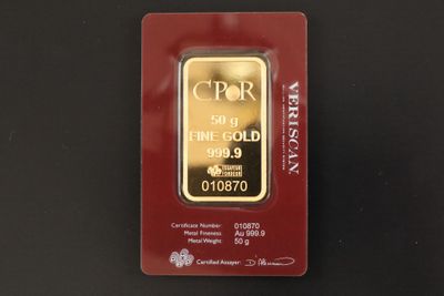 un lingot d'or dans un emballage rouge posé sur une surface noire