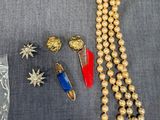 un collier, des boucles d'oreilles et des bracelets en perles dorées disposés sur une surface grise