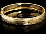 gros plan d'un bracelet en or sur une surface noire