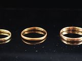 six gold rings are arranged in a row on a black surface