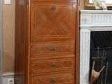 a dresser in front of a fireplace in a room with a painting on the wall