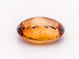 a close up of a faceted citrine gemstone on a white surface